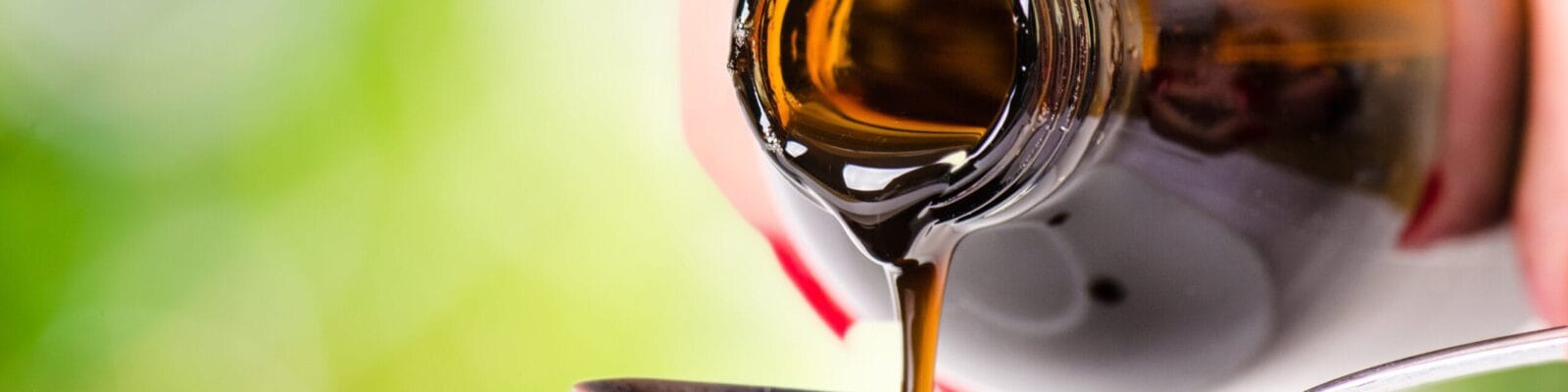 pouring a liquid on a spoon. Natural green background.
