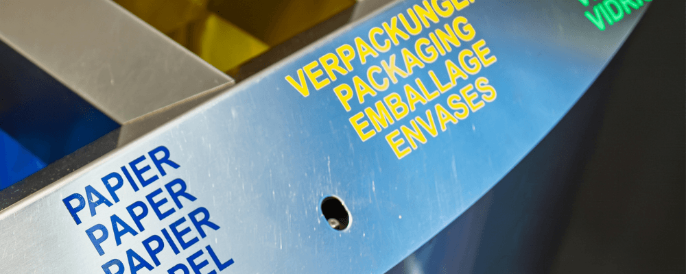 Recycling station with separate waste, paper, packaging and glass compartments, overlaid with the heading “What is PPWR?”